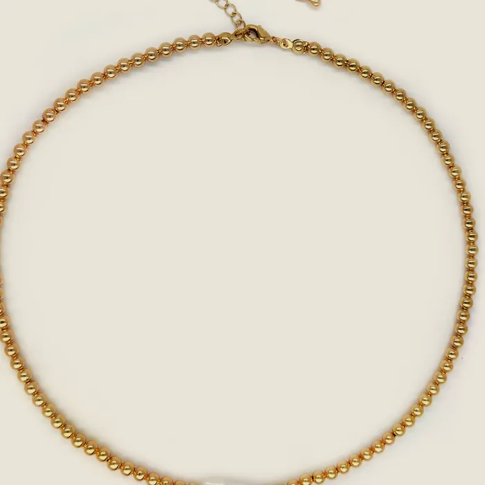 Gold-tone round-link chain necklace with an elongated pearl mounted at the front.