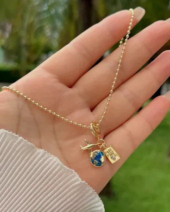 Una cadena con dijes sostenida en la palma de la mano.