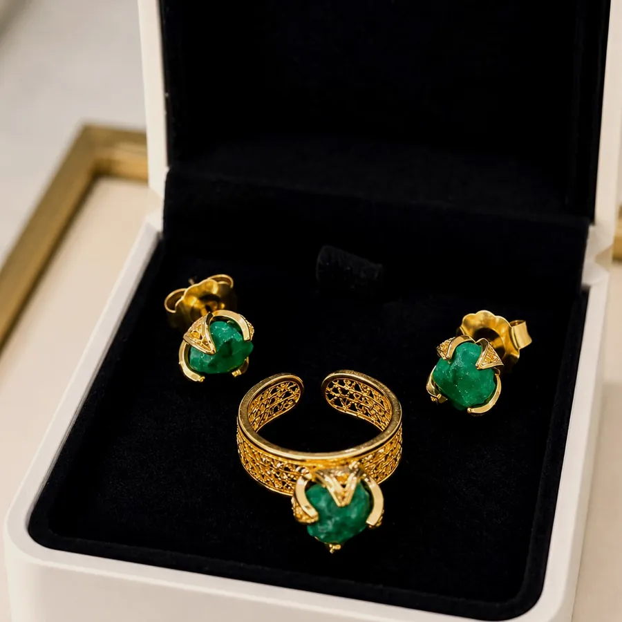 Anillo y aretes con esmeralda en bruto engastada en oro, dentro de un estuche negro.