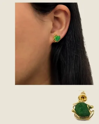 Arete de esmeralda en bruto puesto en la oreja.