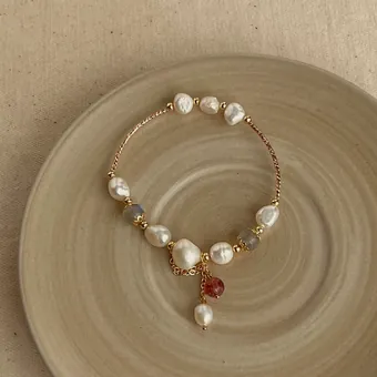 Pulsera de perlas barrocas alternadas con piedras de color y una perla colgando del centro.