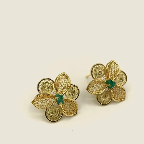 Gold-tone filigree earrings with four petals and a raw emerald at the centre.