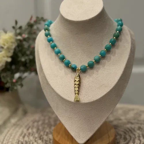 Turquoise necklace with a gold fish pendant.
