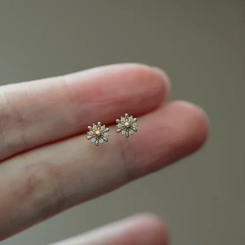 Tiny daisy studs held on a finger.