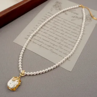 Gold chain with a baroque pearl over a letter sheet.