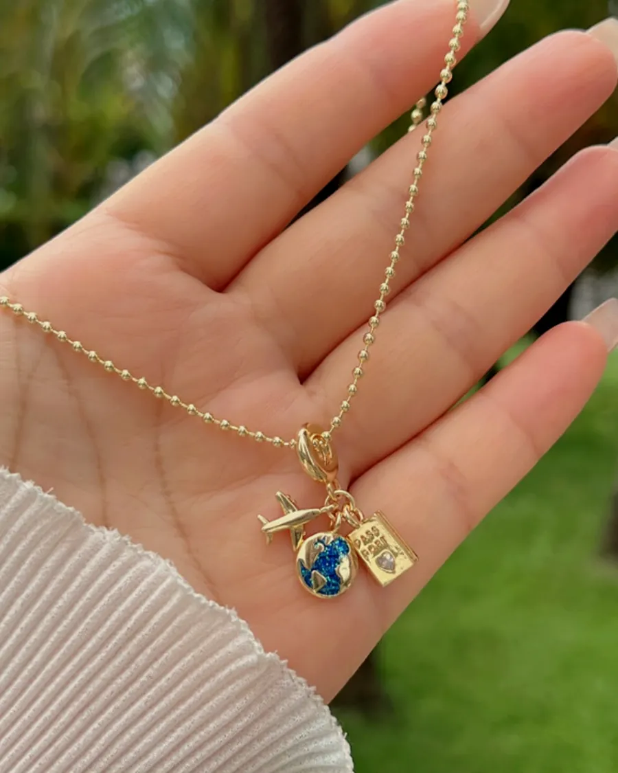 Charm necklace with a blue world, held in the hand.