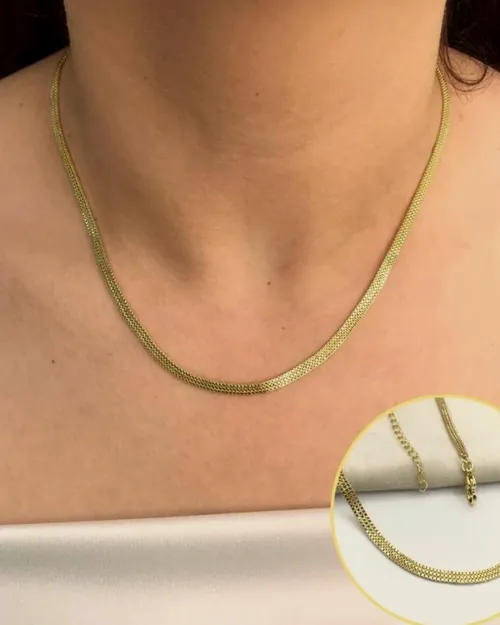 Gold herringbone chain on a white bust.