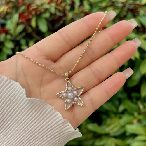 Pearl star necklace held in the hand.