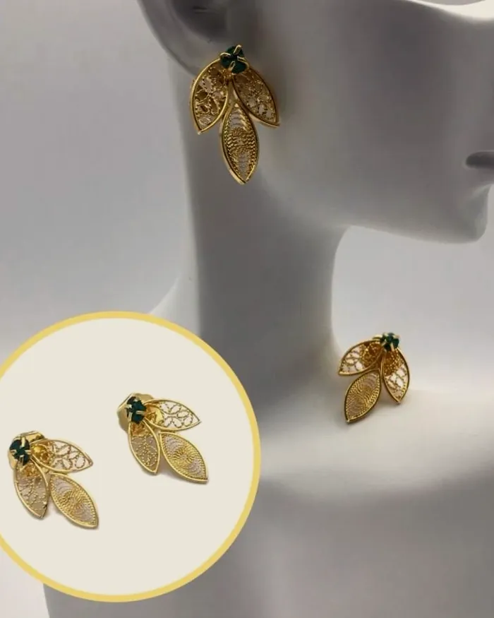 Filigree leaf earrings with emerald on a white bust.