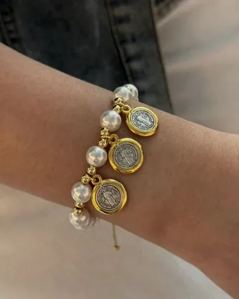 Pearl bracelet with medals, worn on the wrist.