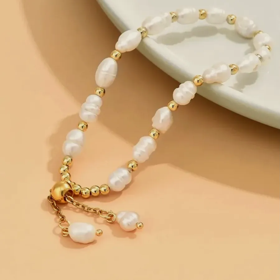 Pearl and gold bead bracelet on a peach background.