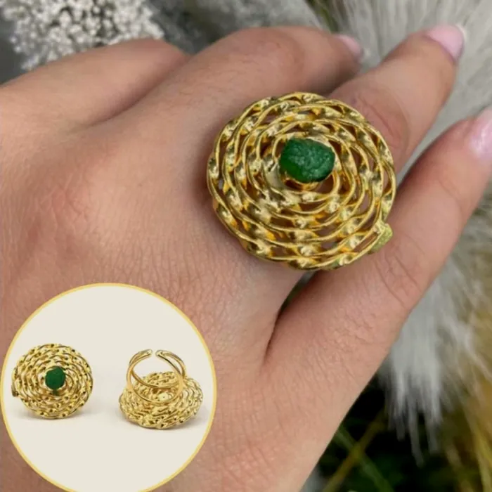 Rosette ring with raw emerald, worn on the hand.