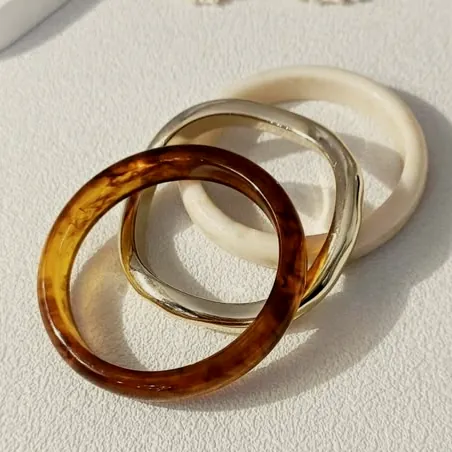 Three rigid resin bangles: tortoiseshell, silver and cream.