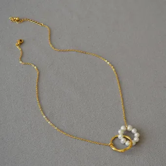 Pearl circle necklace on a grey background.