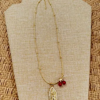 Medal necklace with a garnet bead, on a bust.