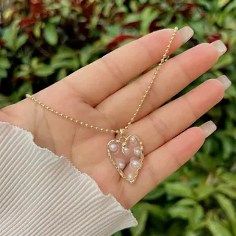 Pearl heart necklace, held in the hand.